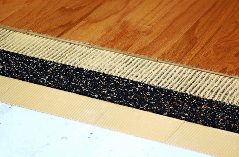 Close-up of Acoustic Cork & Rubber Underlay – 3mm & 4.5mm, showcasing its layered structure with wood, foam/rubber underlay, adhesive, and subfloor, highlighting premium soundproofing and eco-friendly attributes for diverse flooring types.
