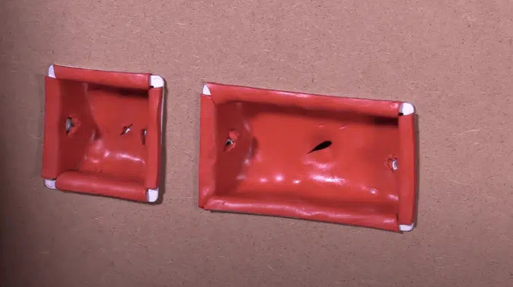 Acoustic & Fire Socket Box Inserts: Two red plastic trays with teardrop holes, designed for soundproofing and noise reduction in drywall installations, ensuring effective acoustic and fire insulation.