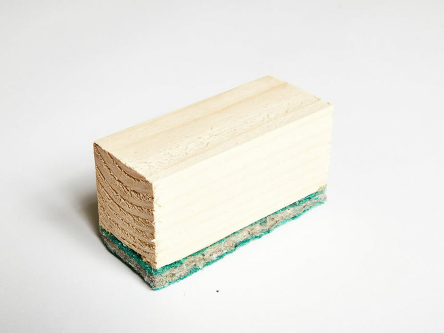 Acoustic Batten 55 for Concrete Floor: A wooden block with a green abrasive scrub pad, ideal for soundproofing and noise reduction in construction, enhancing acoustic insulation in various building projects.