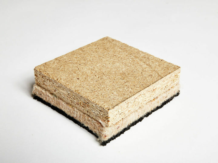 SilentCloud Panel CEM 33 - High Mass Acoustic Floorboard cross-section sample, showing beige chipboard, white fibrous felt, and black rubber layers for soundproofing, noise reduction, and improved sound insulation.