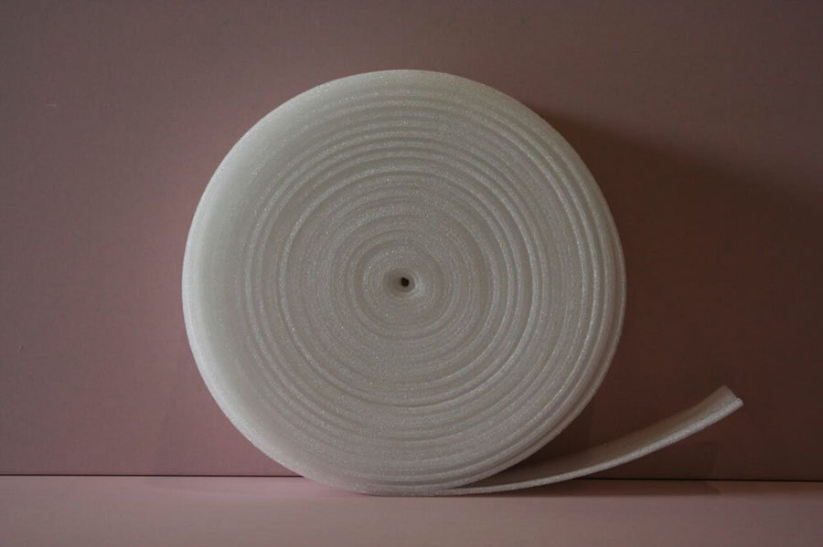 SilentCloud RD Flanking Strip 50m Roll, a large white polyethylene foam, partially unrolled against a pink backdrop, used for soundproofing, acoustic isolation, and noise reduction in construction projects.