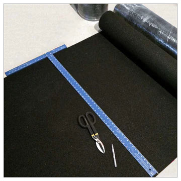 Top view of black SilentCloud FFR acoustic underlay being measured with a blue ruler and scissors ready to cut